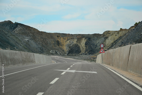 Картината върху платно Mountain road with traffic signs overtaking prohibited and dangerous turn