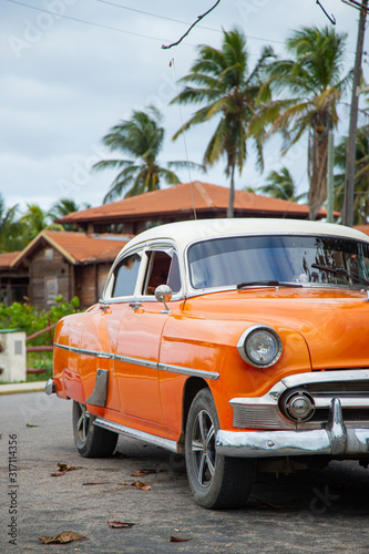 Fototapeta Naklejka Na Ścianę i Meble -  Old retro car of orange color under a palm tree