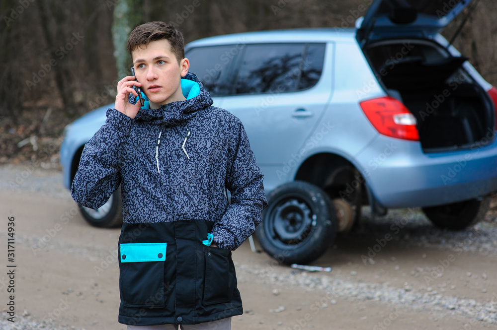 Obraz premium A man struck a wheel on a car and calls the technical service