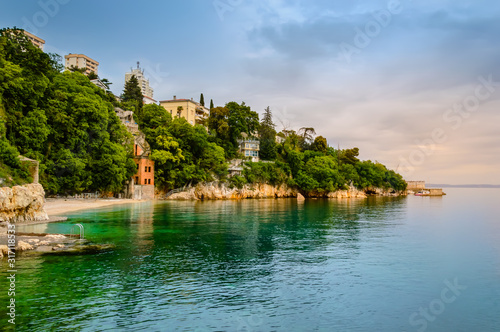 Glavanovo beach in Rijeka, Croatia with steep cliffs and lush green trees photo