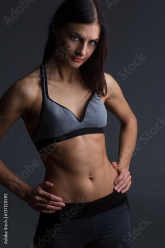 portrait of brunette in a sports top and trousers on a dark background in the Studio