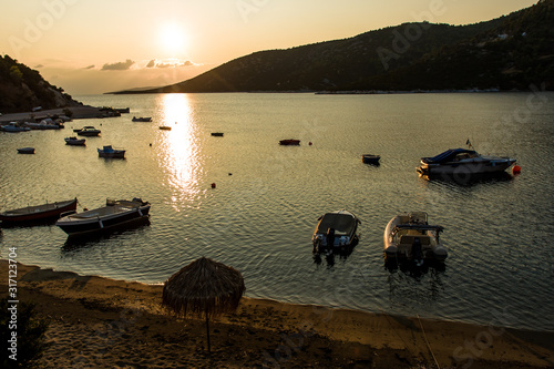 Boats parking in the Mediterranean sea bay, golden light scenery during morning sunrise photo