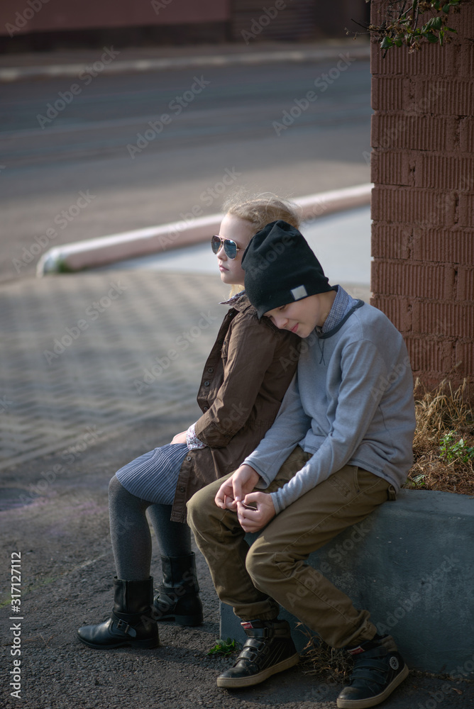 a boy and a curly haired blonde girl in sunglasses on a city street in the summer a boy and a curly haired blonde girl in sunglasses on a city street in the summer