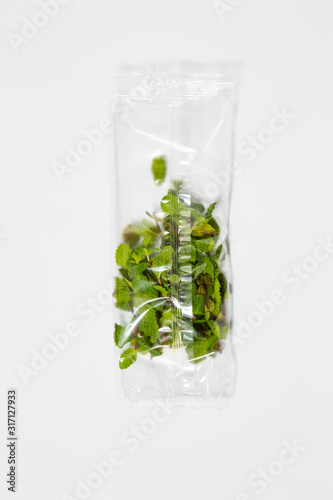 Use less plastic! Mint leaves in plastic packaging isolated on white ground. Symbol for environmental pollution done by the food industry