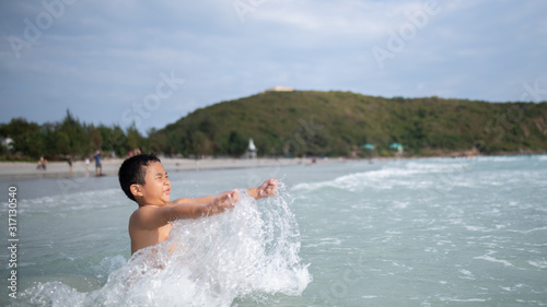 Boy playing  on sandy beach.  Happy kid on vacations at seaside on summer holidays. Children in nature with sea, sand and blue sky. © mai111