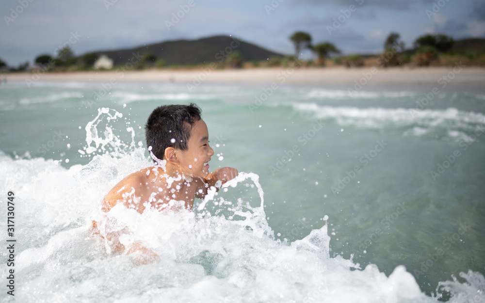 Boy playing  on sandy beach.  Happy kid on vacations at seaside on summer holidays. Children in nature with sea, sand and blue sky.