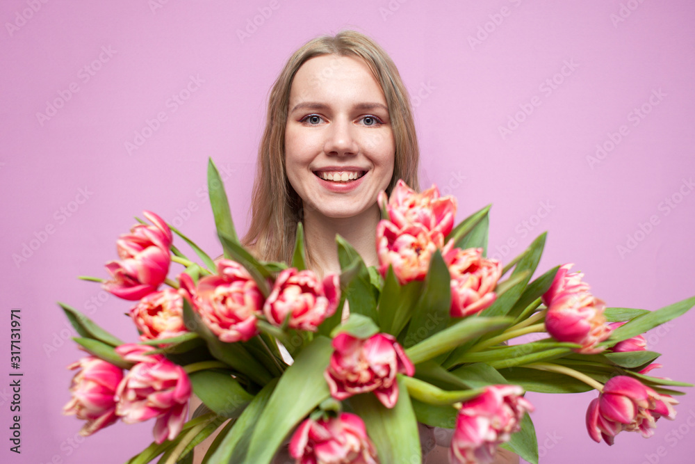 girl holds and sniffs a bouquet of flowers on a pink background, a beautiful woman with tulips girl holds and sniffs a bouquet of flowers on a pink background, a beautiful woman with tulips