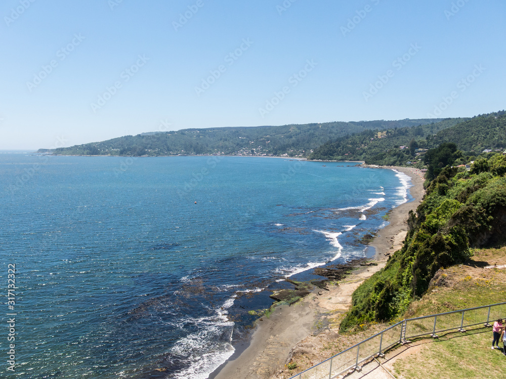 Fototapeta premium Beach lovers facing the Pacific Ocean from the fort of Niebla village. Estuary and mouth of the Valdivia River. Valdivia, Los Rios Region, South of Chile