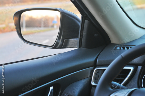 Car interior with a side-view mirror and countryside road
