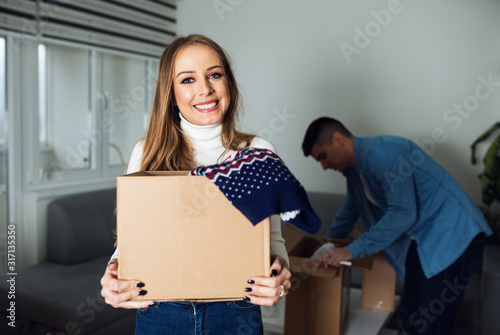 Happy young woman holding carton box in new home © Novak