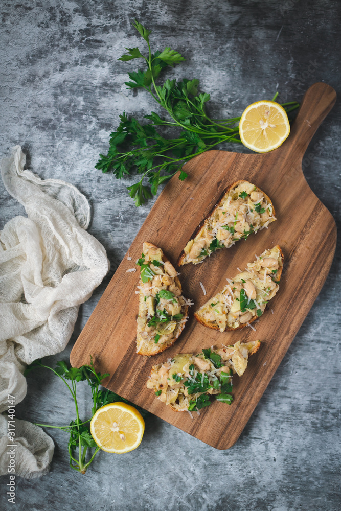 Toast slices with white lemon beans on top, styled dark background Toast slices with white lemon beans on top, styled dark background