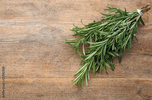 Bunch of fresh rosemary on wooden table, above view. Space for text