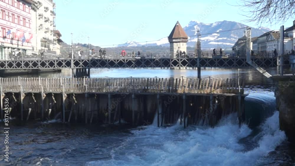 The famous wooden Kappel bridge with the watertower in Luzern, Switzerland, with blue sky and the mountains in the background