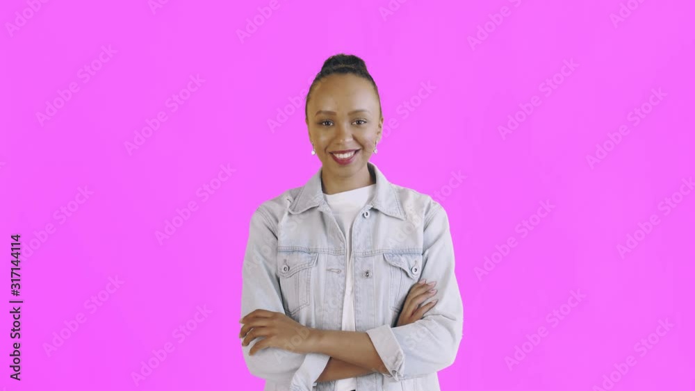 Shoot of young african american woman smiling happily having her arms crossed looking at camera on pink background Jean jacket Shoot of young african american woman smiling happily having her arms crossed looking at camera on pink background Jean jacket