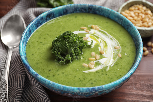 Tasty kale soup served on wooden table, closeup