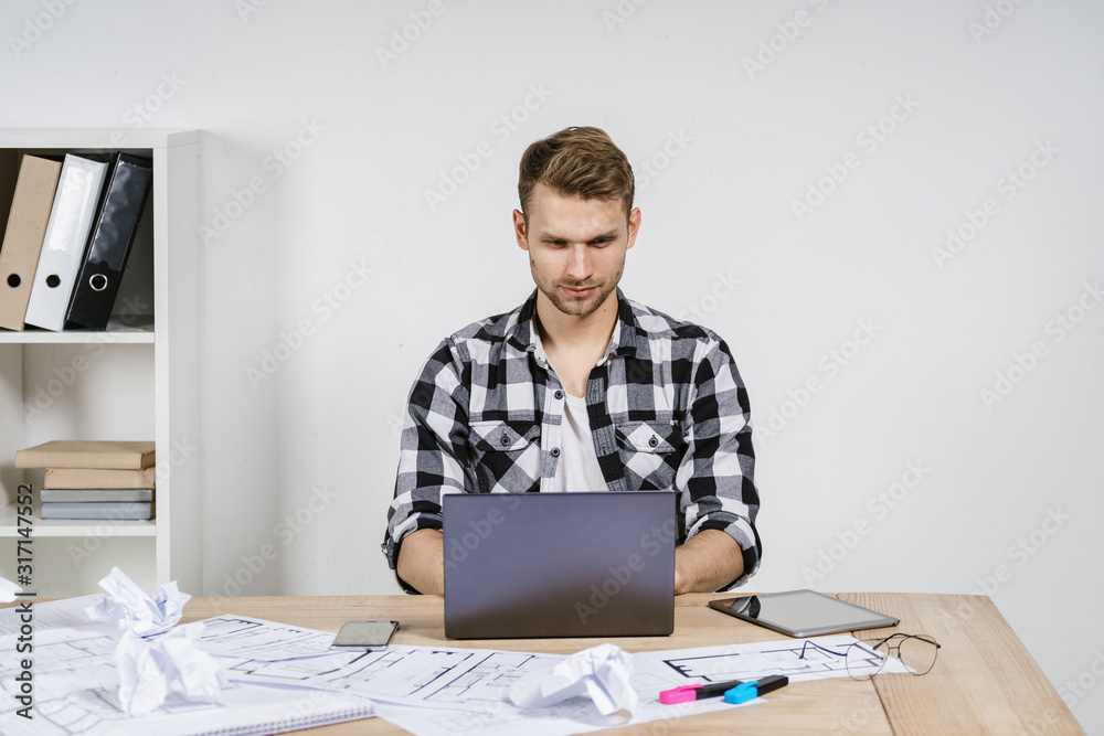 Young adult architect and designer working with blueprints in workspace office Young adult architect and designer working with blueprints in workspace office