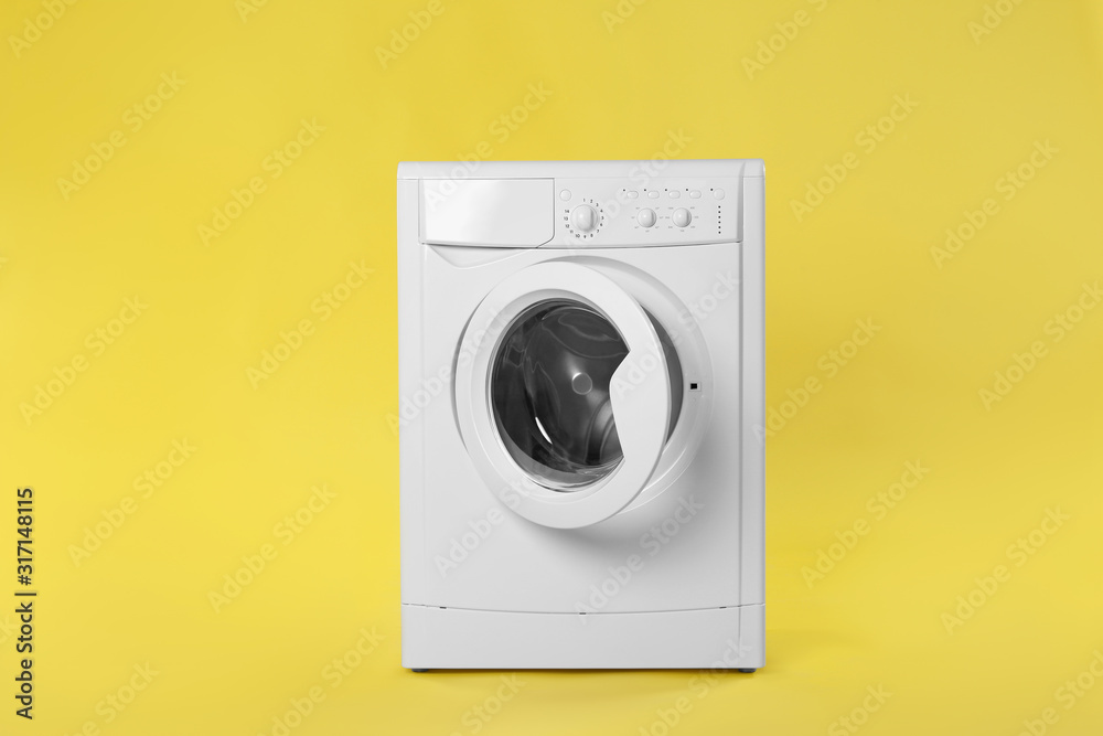 Modern washing machine on yellow background. Laundry day