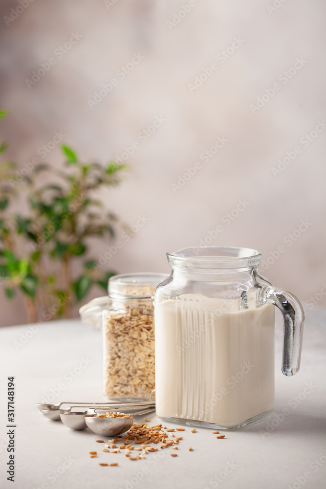 Vegan oat milk, non dairy alternative milk in a glass. Oat flakes on stone table. Vegan oat milk, non dairy alternative milk in a glass. Oat flakes on stone table.