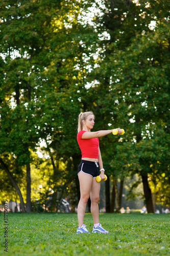 Fototapeta Naklejka Na Ścianę i Meble -  A young woman goes in for sports outdoors. girl with blond hair is training in the park on the nature