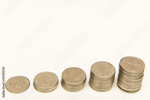 Canadian Quarters stacked into five ascending piles on white background.