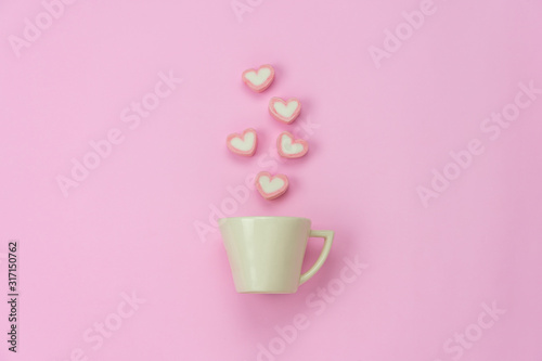 Table top view aerial image of sign valentine's day background concept.Flat lay arrangement white coffee cup with steam heart shape on modern pink paper at home office desk studio.Pastel tone design.