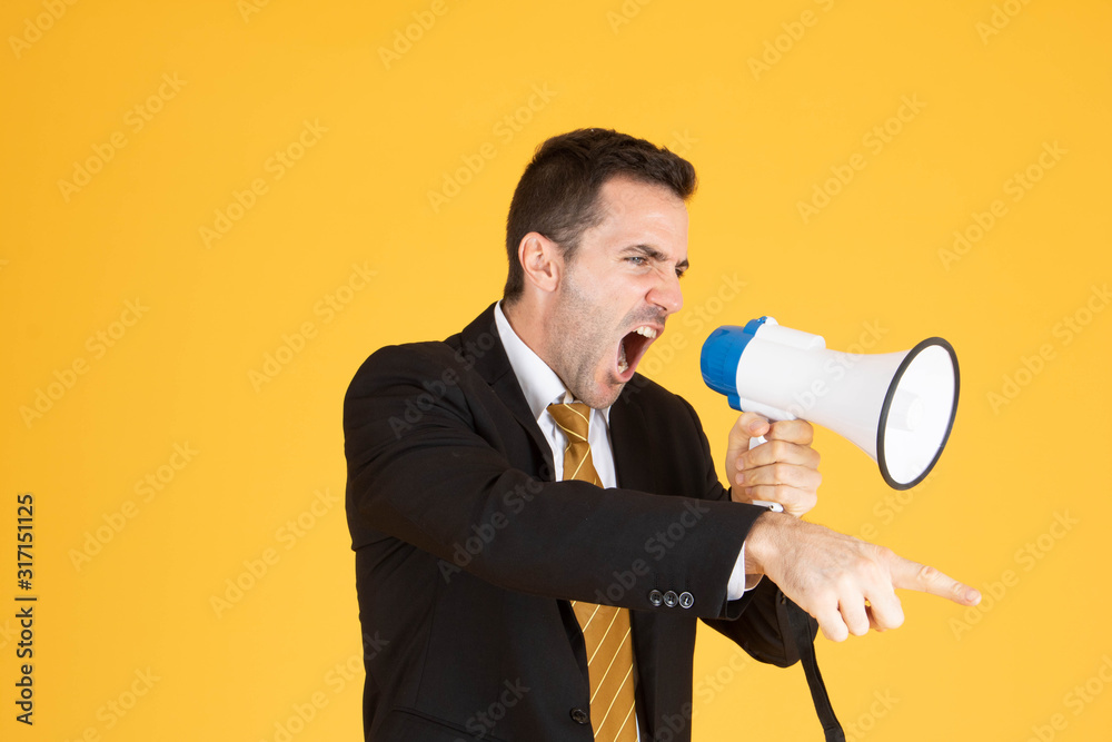 Portrait of a handsome businessman wearing white suit and tie while using megaphone, screaming with yellow background. Portrait of a handsome businessman wearing white suit and tie while using megaphone, screaming with yellow background.