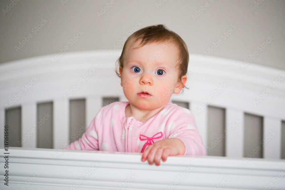 Very Cute 10 Month Old Baby Girl with Big Blue Eyes Playing in the White Crib Very Cute 10 Month Old Baby Girl with Big Blue Eyes Playing in the White Crib