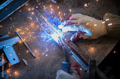 Metal welding. Sparks from electric heating. Work in the workshop. Creation of reliable fastening of materials. Fabrication of iron. The work of the master of metal.