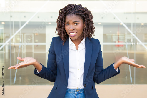 Fotografie Doubtful young businesswoman looking at camera