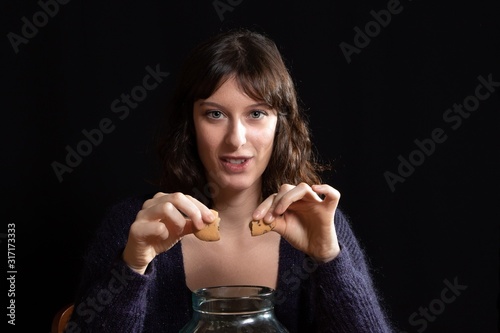 Canvas Close-up of woman breaking a biscuit over a transparent jar