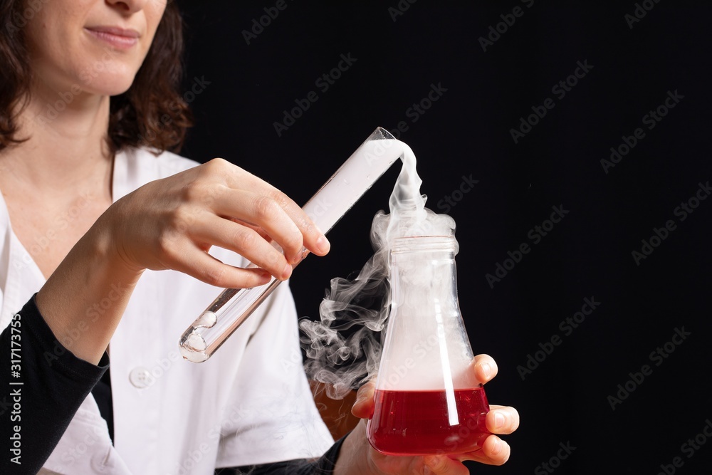 Φωτογραφία Detail of woman pouring liquids into an ampoule with chemical reaction fumes
