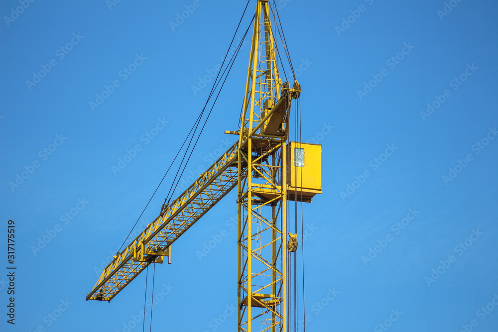 Orange tower crane against a blue sky. Construction of a new brick building. Housing on credit, mortgages, sale of real estate.  An emerging housing market under construction. Copy space