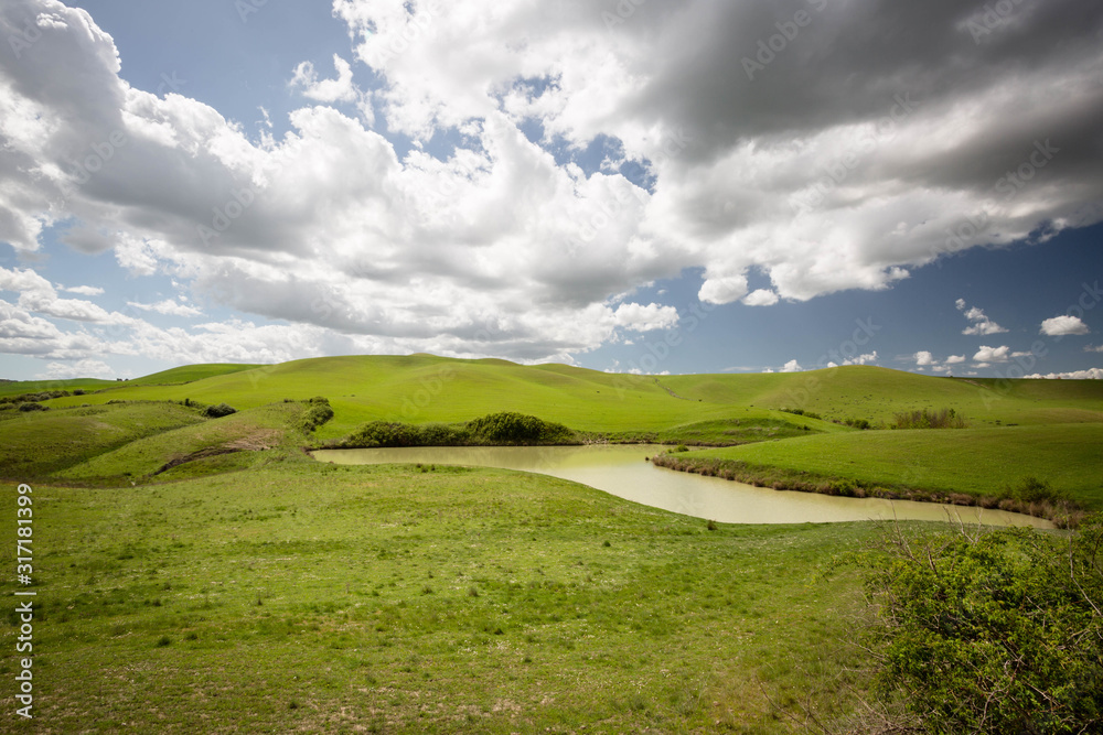 Colline Toscane con laghetto in primo piano immerso nelle verdi colline Colline Toscane con laghetto in primo piano immerso nelle verdi colline