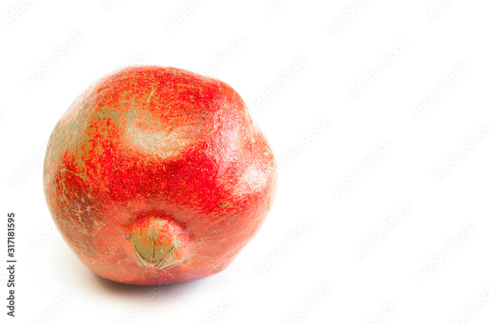 Red ripe pomegranate lies on a table on a white background. Red ripe pomegranate lies on a table on a white background.