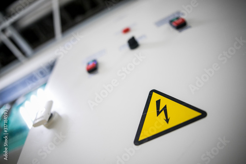 Sign danger high voltage. Sign dangerously high voltage electricity. A yellow triangle mark with a lightning bolt in the center. This warning is painted on an old metal surface painted with gray paint photo