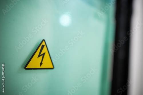 Sign danger high voltage. Sign dangerously high voltage electricity. A yellow triangle mark with a lightning bolt in the center. This warning is painted on an old metal surface painted with gray paint photo