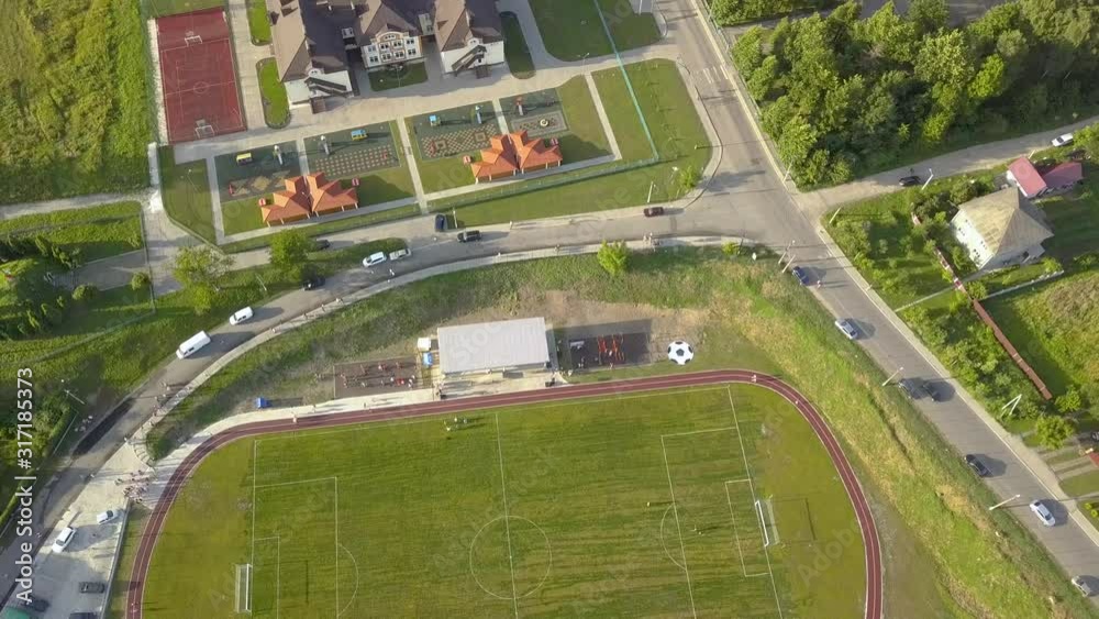Aerial view of a football field on a stadium covered with green grass in rural town area. Aerial view of a football field on a stadium covered with green grass in rural town area.