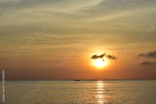 Sunrise above sea near Amed in Bali with tiny silhouettes of local boats far away on ocean surface.