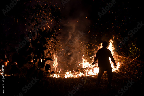 A forest fire that is burning a forest with a man who controls the fire