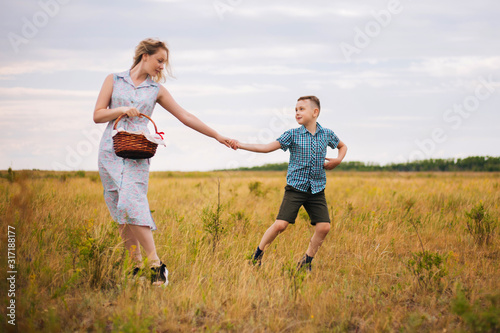 Mother and son. The boy holds his mother by the hand. Family walks in the field.