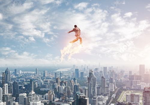 Businessman in suit and aviator hat flying in sky