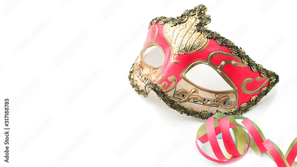 Magenta venetian carnival mask on white table with some stream