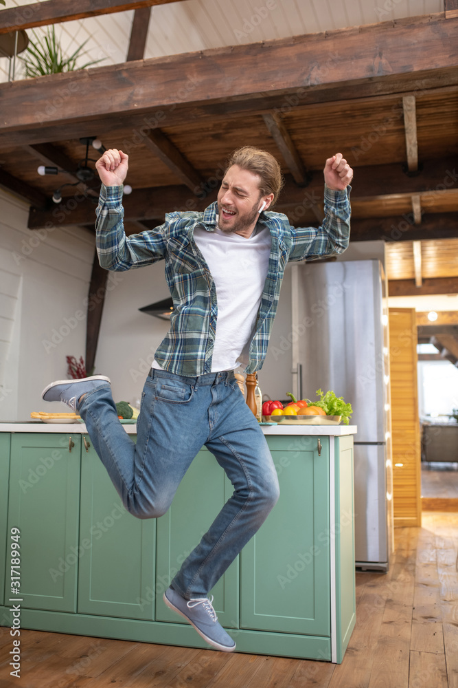 Joyful and energetic man jumping in his kitchen