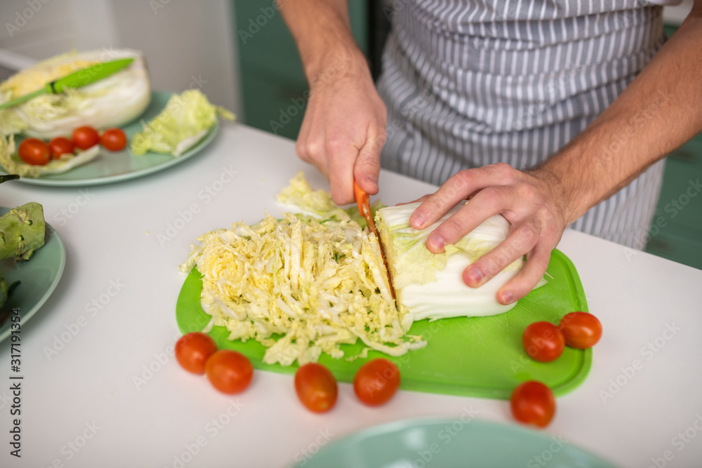 Cook cutting cabbage for a vegetable salad Cook cutting cabbage for a vegetable salad
