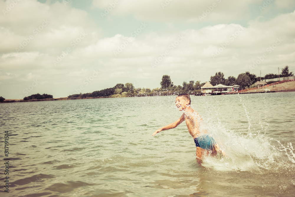 Carefree boy running in the water during summer day.