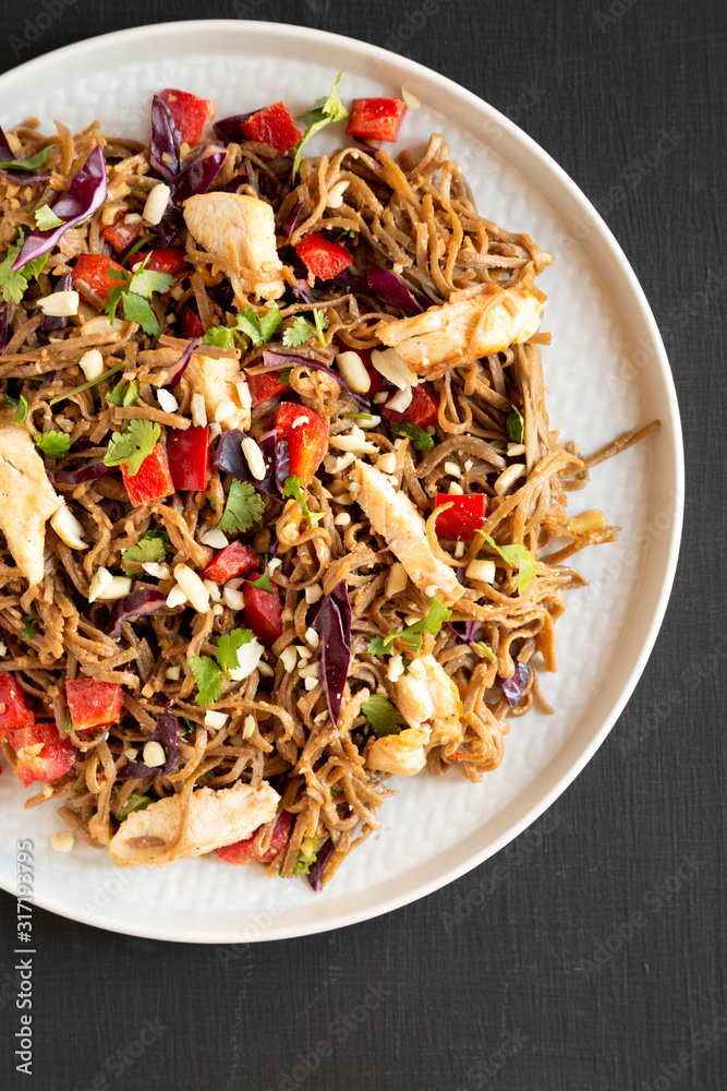 Homemade Spicy Chicken Soba Noodle Salad on a gray plate on a black surface, top view. Flat lay, overhead, from above.