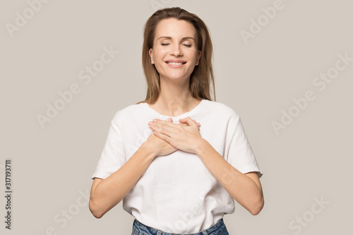 Obraz na płótnie Happy grateful woman hold hands at chest feeling thankful