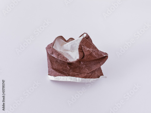 One, crumpled, brown disposable glass on a white background. Used. Close-up. Disposable tableware. 
