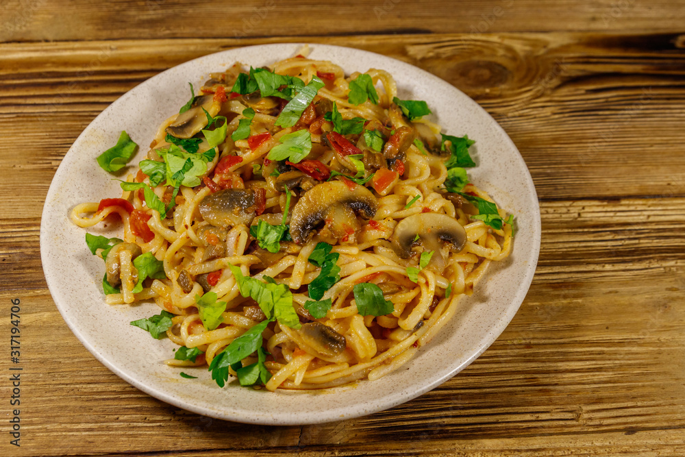 Pasta with mushrooms and tomato sauce on wooden table Pasta with mushrooms and tomato sauce on wooden table