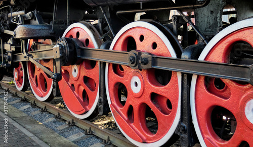 Old steam engine locomotive wheels and other parts, close-up view. Black and red iron details of vintage train. Industrial retro background.